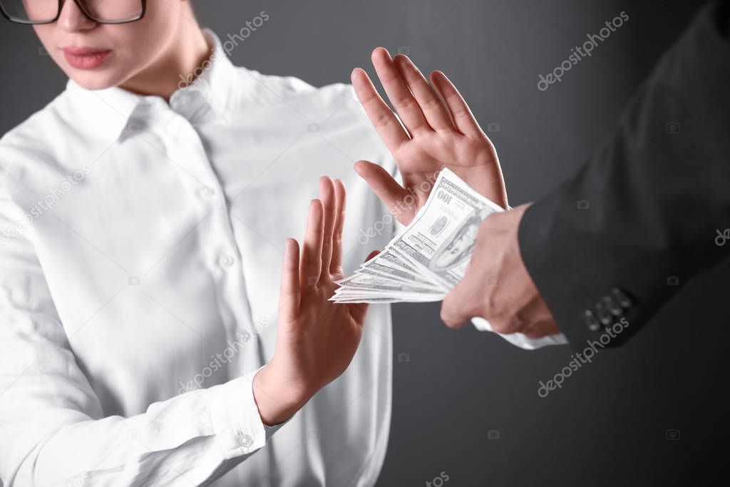 Woman refuses to take bribe money on dark background, closeup