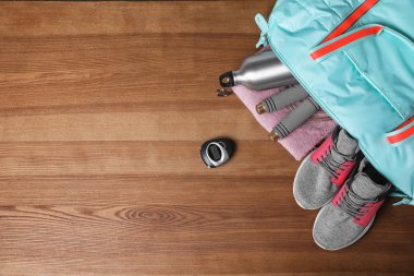 Tahta arka planda spor eşyaları olan spor çantalarını aç, düz yat. Evet.