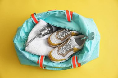 Gym bag with sports equipment on yellow background, top view clipart