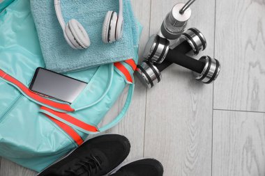 Spor çantası ve spor malzemeleri ahşap zeminde, manzaranın üstünde.