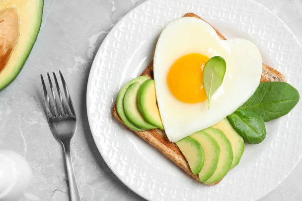 Вкусный завтрак с жареным яйцом в форме сердца подается на серой табличке — стоковое фото