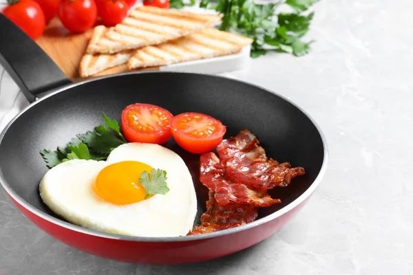 Smaczne śniadanie ze smażonym jajkiem w kształcie serca na szarym stole — Zdjęcie stockowe