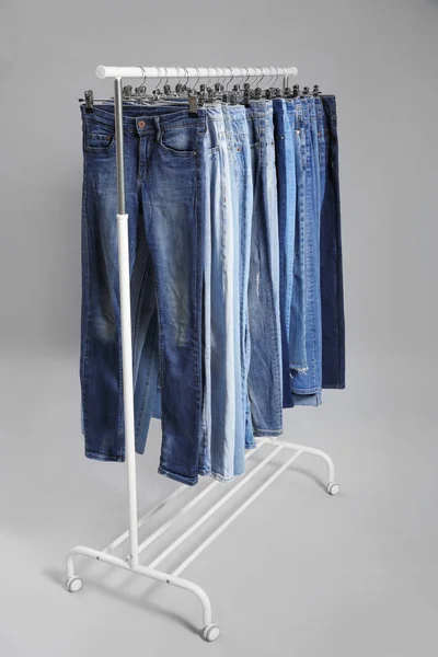 Scaffale con diversi jeans su sfondo grigio — Foto Stock