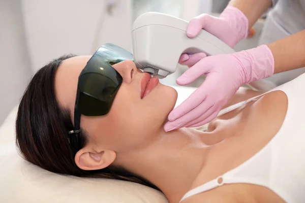 Young woman undergoing laser epilation procedure in beauty salon — Stock Photo, Image