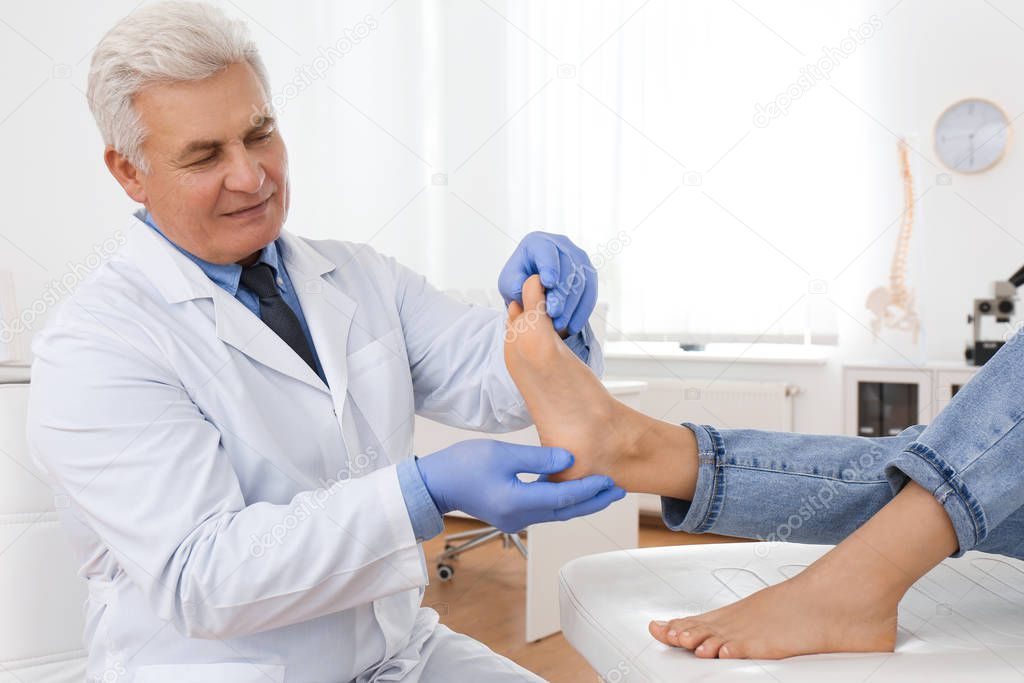 Male orthopedist checking patient's foot in clinic