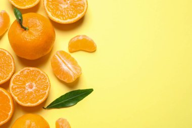 Düz kompozisyonda taze mandalinalar ve açık sarı arka planda yapraklar vardı, yazı için boşluk. Citrus meyvesi.