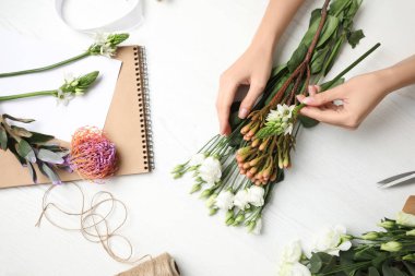 Çiçekçi beyaz ahşap masada güzel bir buket yapıyor.