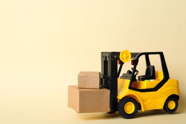 Bej arka planda kutuları olan oyuncak forklift, metin için boşluk. Lojistik ve toptan satış kavramı