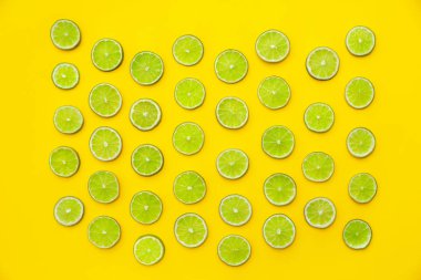 Sarı arka planda taze sulu limon dilimleri, düz uzanmış.