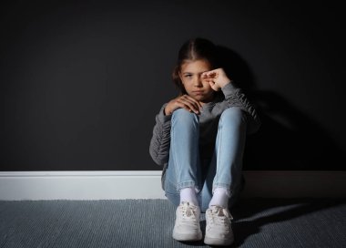 Kara duvarın yanında üzgün küçük bir kız. Aile içi şiddet kavramı