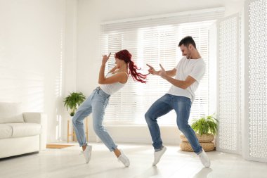Güzel, genç bir çift oturma odasında dans ediyor.
