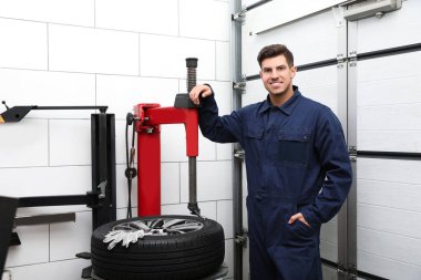 Araba servisindeki lastik montaj makinesinin yanındaki adam.