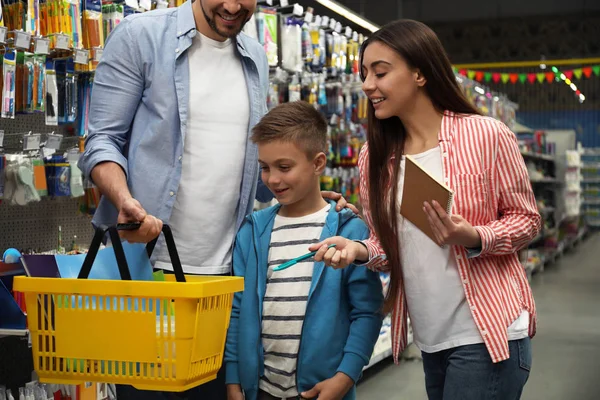 Family with little boy choosing school stationery in supermarket