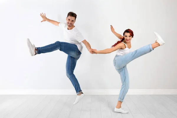 Hermosa pareja joven bailando cerca de pared de luz —  Fotos de Stock