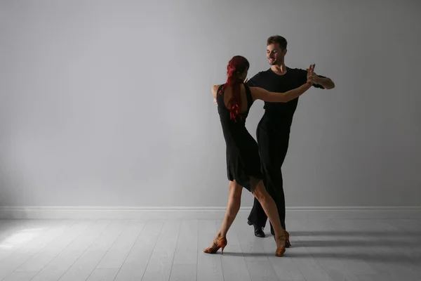 Hermosa pareja joven bailando cerca de la pared de luz. Espacio para texto — Foto de Stock