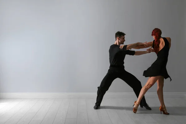 Hermosa pareja joven bailando cerca de la pared de luz. Espacio para texto — Foto de Stock