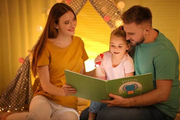 Rodina s baterkou čtení knihy doma — Stock fotografie