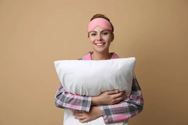 Beautiful woman with pillow on beige background. Bedtime — ストック写真
