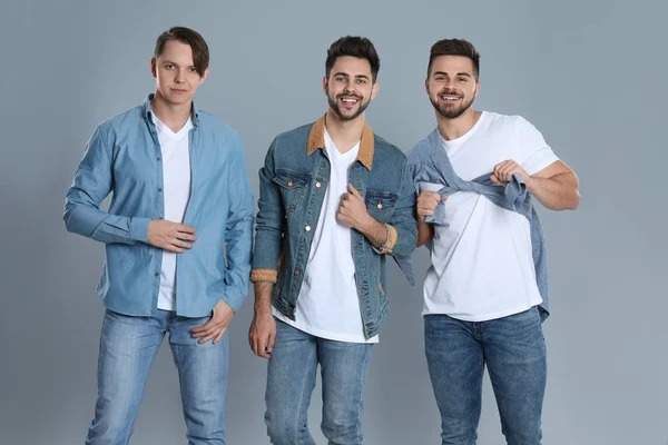 Group of young men in stylish jeans on grey background — Stock Photo, Image