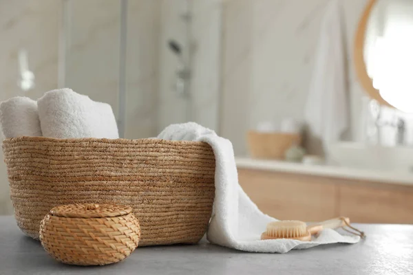 Proutěný koš s čistými ručníky a masážní kartáč na stole v ba — Stock fotografie