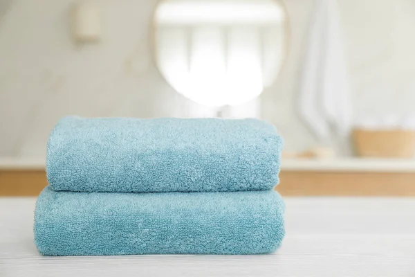 Pila di asciugamani puliti su tavolo di legno bianco in bagno — Foto Stock