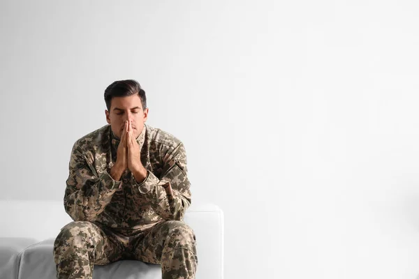 Stressed military officer sitting on sofa against white backgrou — ストック写真