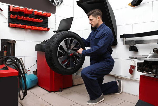 Man working with wheel balancing machine at tire service