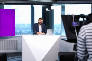 Sunucu ve kamera operatörü stüdyoda çalışıyor. Haber yayını