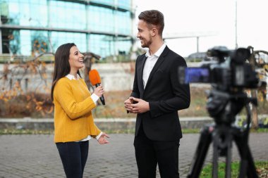 Genç gazeteci şehir sokaklarında iş adamıyla röportaj yapıyor.