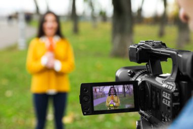 Park 'ta çalışan genç gazeteci ve video operatörü, kamera ekranına odaklanın