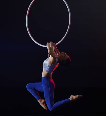 Genç bir kadın hava halkası üzerinde akrobatik bir element sergiliyor. 