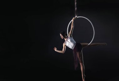 Genç bir kadın hava halkası üzerinde akrobatik bir element sergiliyor. 