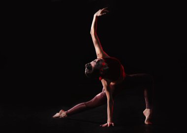 Genç bir kadın sahnede akrobatik hareketler yapıyor.