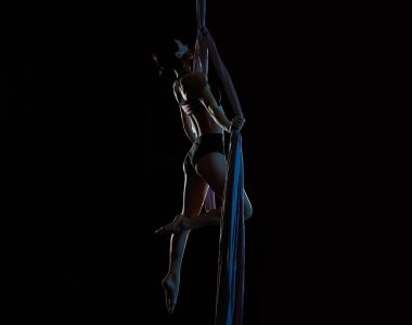 Genç bir kadın içerideki hava ipeklerinde akrobatik hareketler yapıyor.