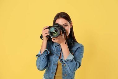 Stüdyoda sarı arka plan üzerinde çalışan profesyonel fotoğrafçı.