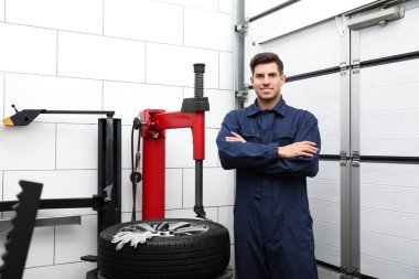 Araba servisindeki lastik montaj makinesinin yanındaki adam.