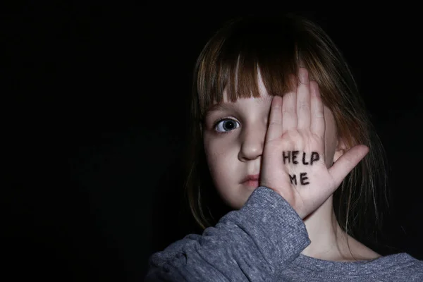 Missbrauchtes kleines Mädchen zeigt Handfläche mit Satz helfen mir auf schwarzem Bac — Stockfoto