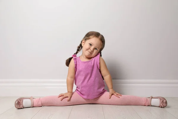 Linda niña en el suelo cerca de la pared gris claro — Foto de Stock