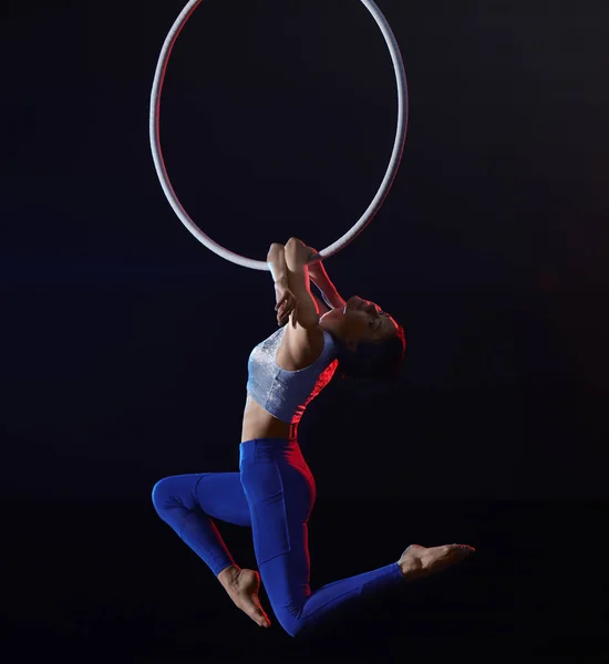 Mujer joven realizando elemento acrobático en anillo aéreo contra — Foto de Stock