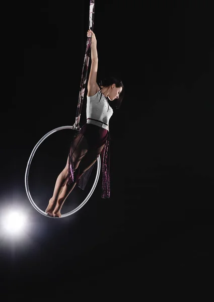 Giovane donna che esegue elemento acrobatico su anello aereo al chiuso — Foto Stock