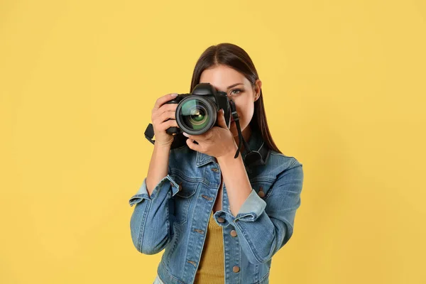 Профессиональный фотограф работает на жёлтом фоне в студии — стоковое фото