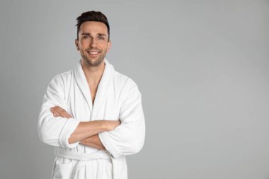 Açık gri arka planda bornozlu mutlu genç adam. Metin için boşluk