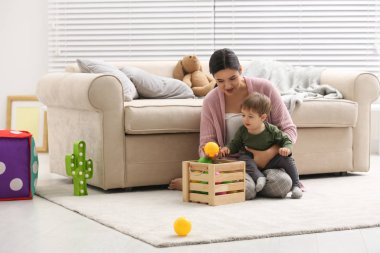 Genç dadı ve sevimli bebek evde oyuncaklarla oynuyorlar.
