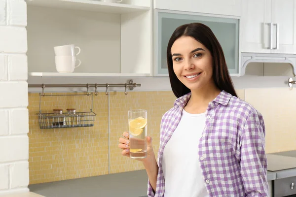 Bella giovane donna con acqua di limone in cucina — Foto Stock