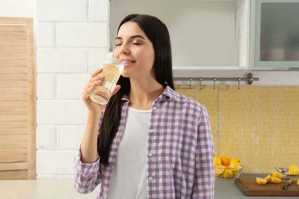 Bella giovane donna che beve acqua al limone in cucina — Foto Stock