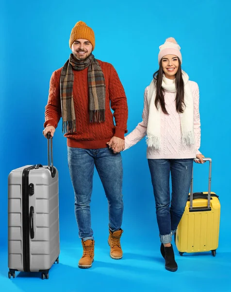 Boldog Fiatal Pár Meleg Ruhában Kék Hátterű Bőröndökkel Téli Vakáció — Stock Fotó