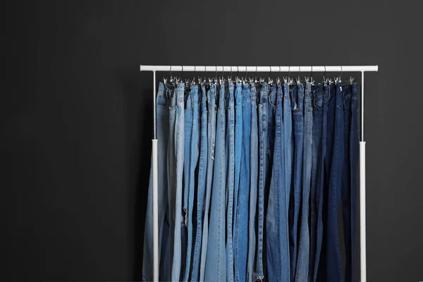 Scaffale con jeans diversi su fondo grigio scuro — Foto Stock