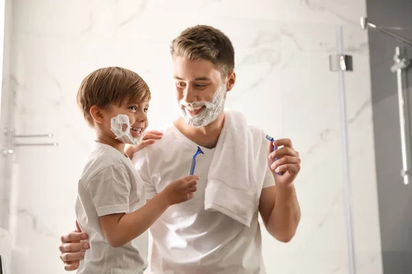 Papá e hijo con espuma de afeitar en sus caras divirtiéndose en el baño — Foto de Stock