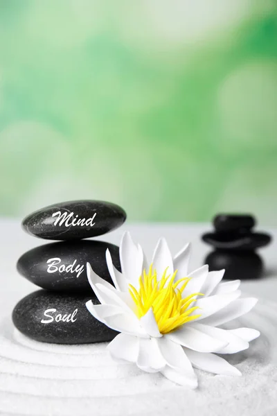 Stones with words Mind, Body, Soul and lotus flower on white sand. Zen garden