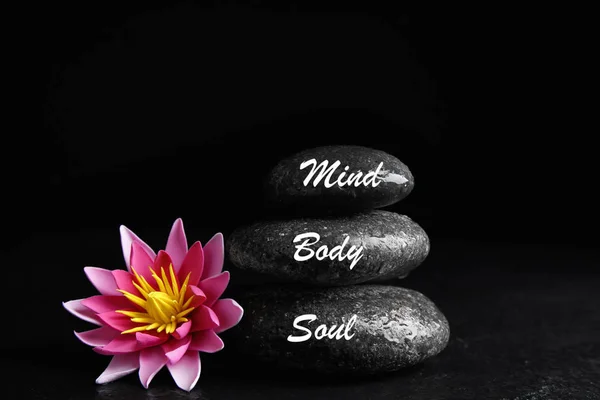 Stones with words Mind, Body, Soul and lotus flower on black background. Zen lifestyle